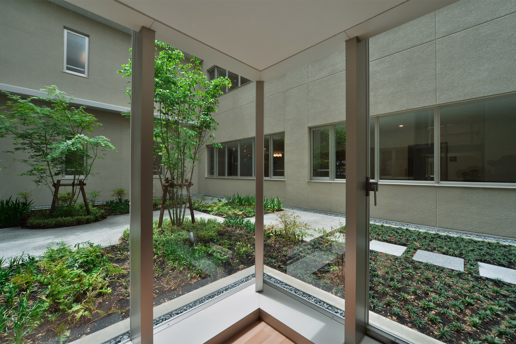 Nabari Intensive Nursing Home Courtyard enclosed by a corridor flooded with natural light.