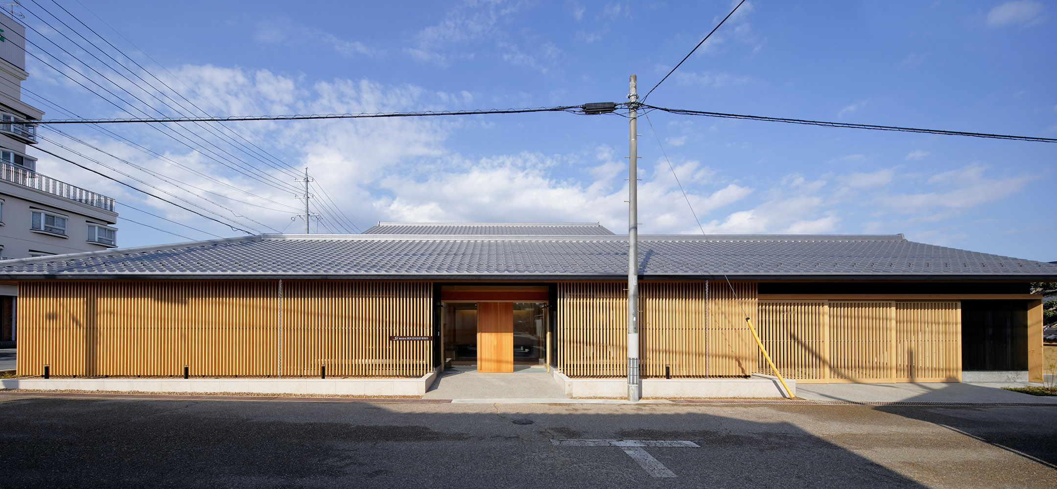 周辺環境・景観の連続性を配慮し、おおらかな瓦屋根と連続した面格子でオフィスと駐車場を一体化。