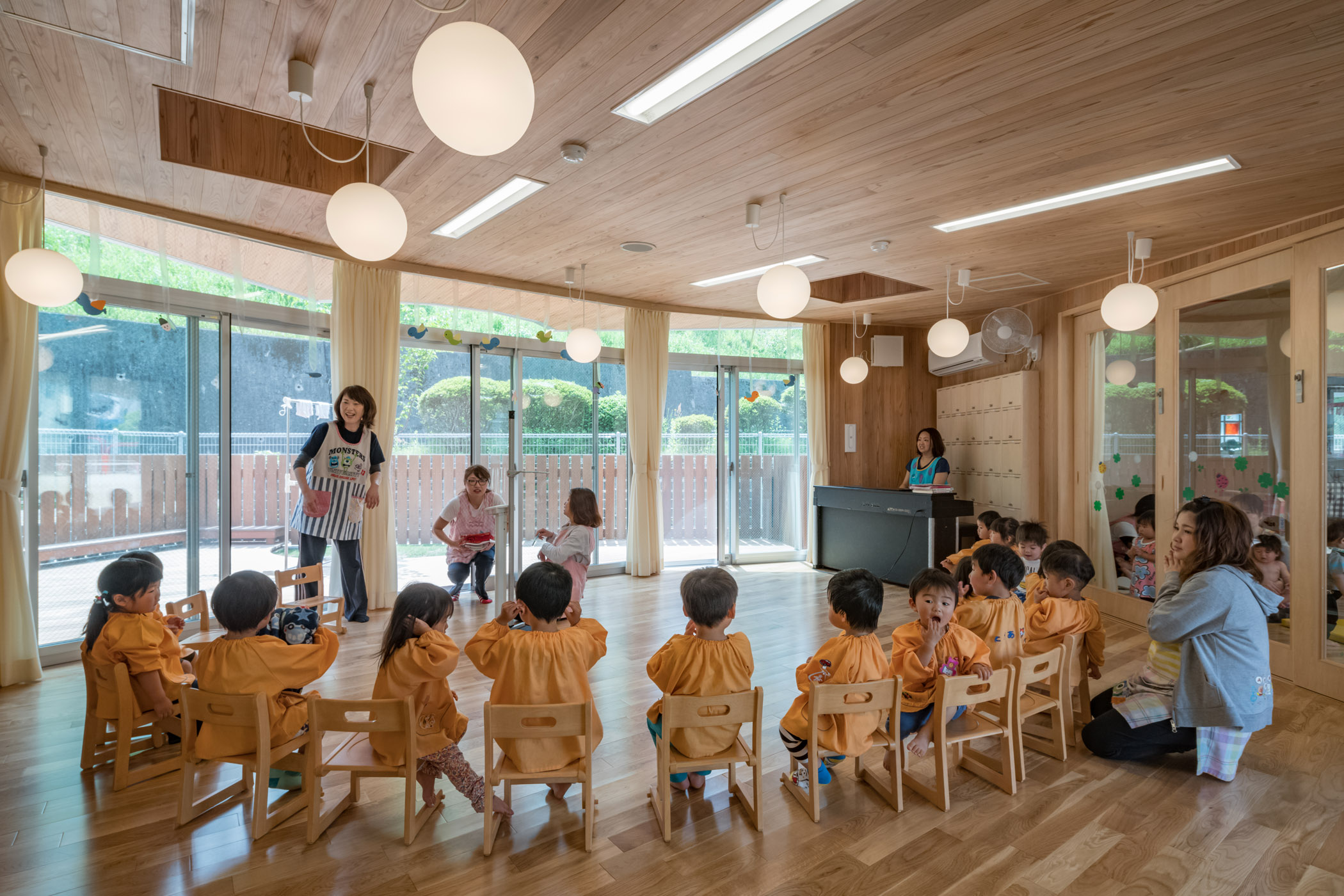 共用利用できるホール空間で歌う園児たち。杉板天井が特徴。